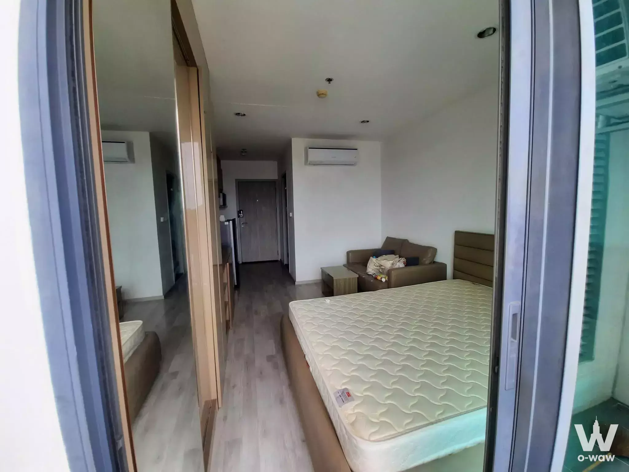 Modern 1-bed condo bedroom in Ideo Mobi Charan Interchange with grey laminate floors, queen bed, and balcony access