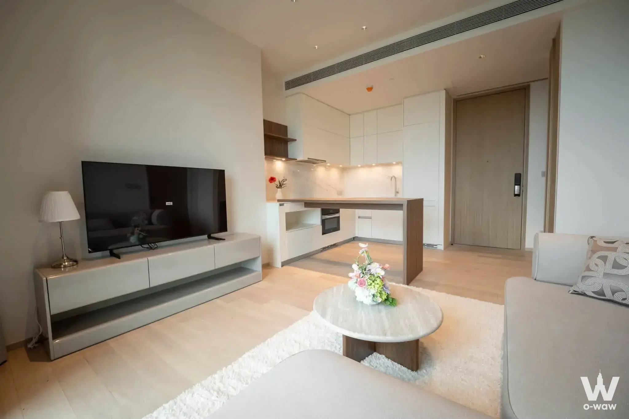 EI8HTEEN SEVEN open-plan living area with glossy white kitchen island, marble coffee table, and neutral tones