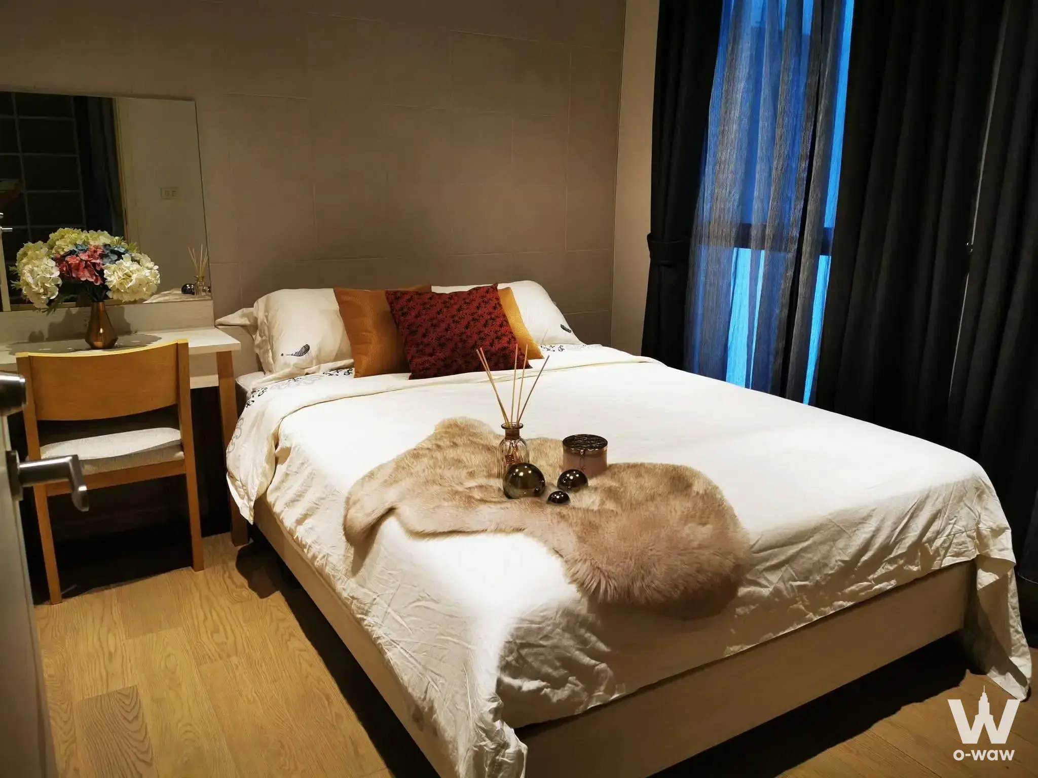 Queen bed in a Runesu Thonglor 5 1-bed condo with mustard pillows and floor-to-ceiling twilight windows