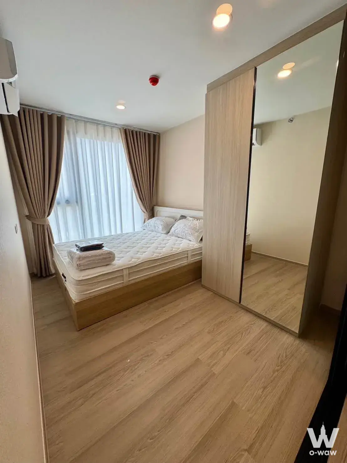 Bright 1-bed bedroom at Origin Play Bangkhunnon with oak floors, mirrored wardrobe, and sheer curtains letting in natural