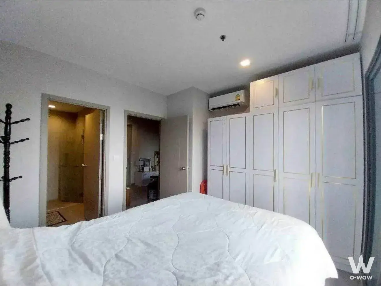 Master bedroom in The Politan Aqua with white built-in wardrobes, gold handles, and a queen bed