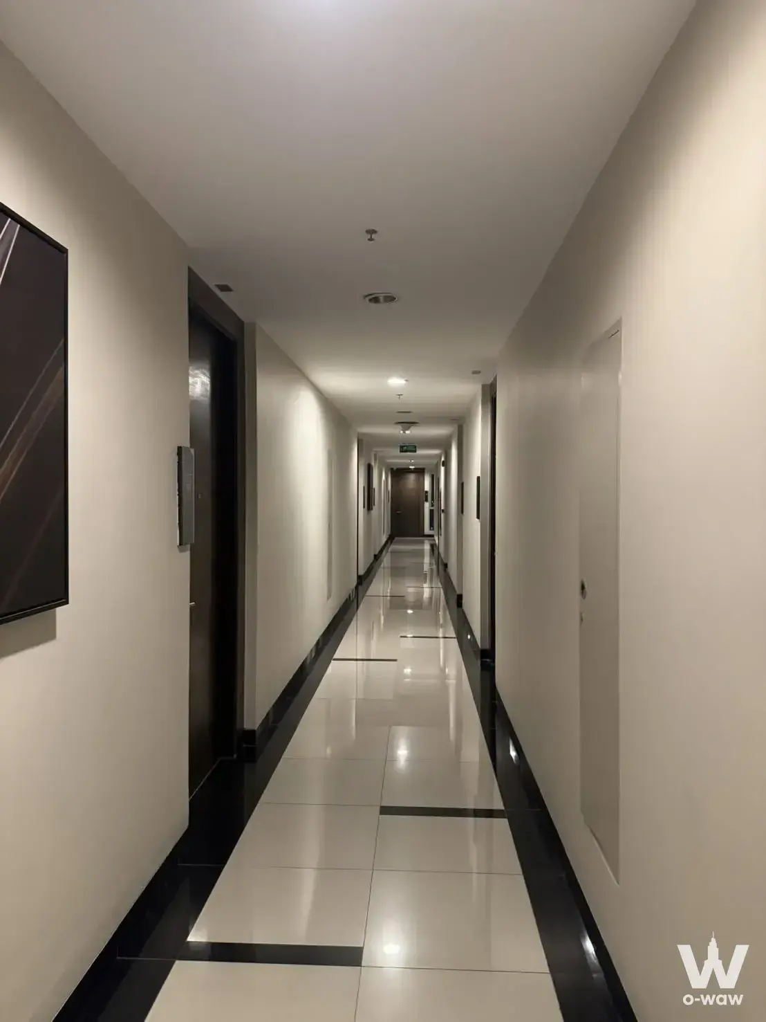Modern hallway with glossy white tiles and black accents in RHYTHM Phahon-Ari 1-bed condo for rent