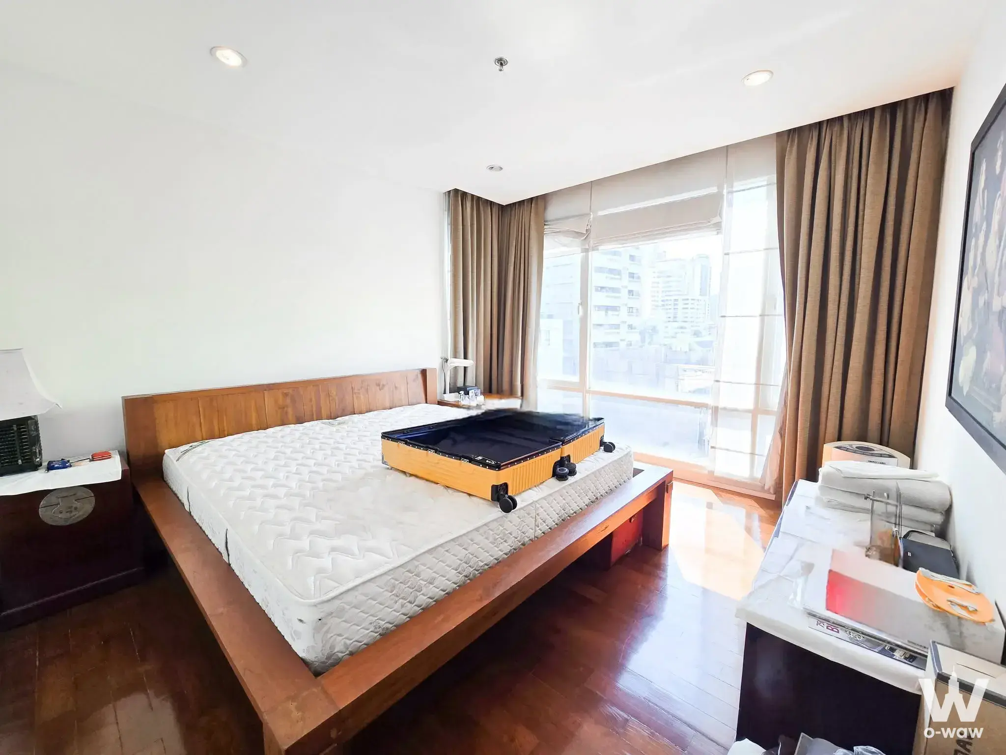 Unmade queen bed with open suitcase in this 2-bed condo for sale in Baan Siri Thirty One