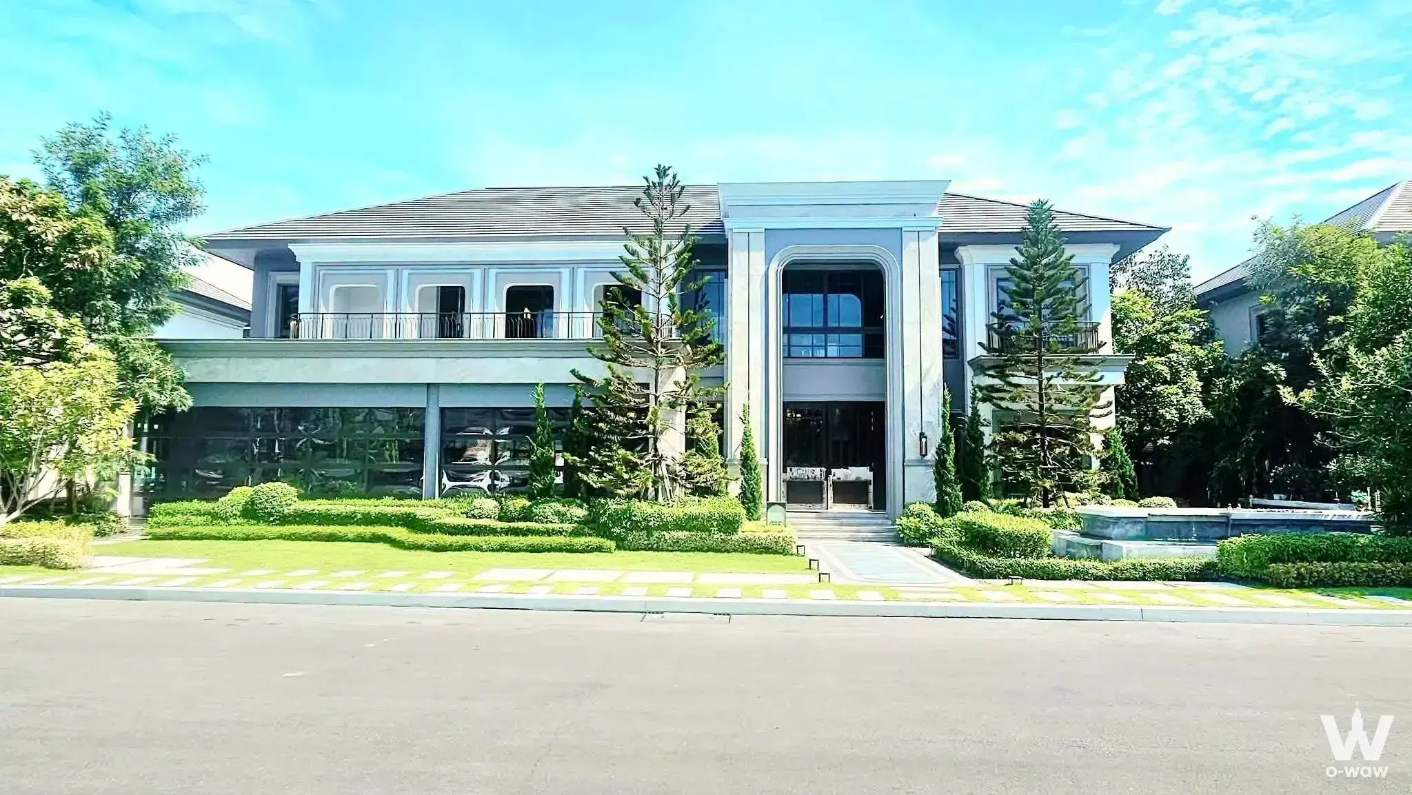 Modern classical villa exterior with grey facade, arched entrance, and manicured lawn in Grand Bangkok Boulevard Sathorn