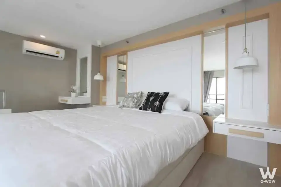 Minimalist master bedroom at KnightsBridge Prime Sathon with white bedding and light oak built-in headboard