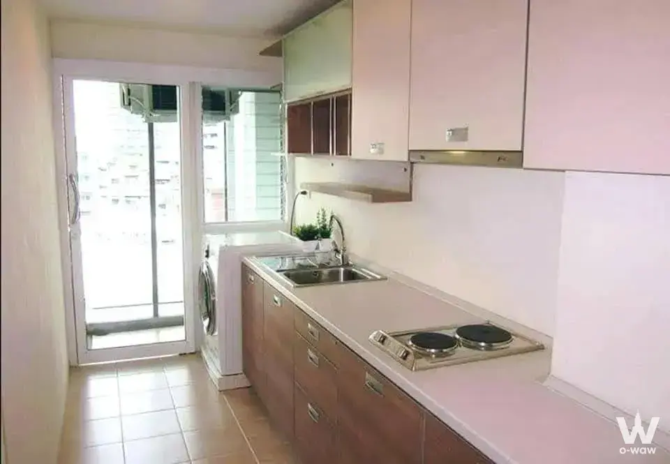 Compact L-shaped kitchen with beige counters and stainless sink in a 2-bed condo for rent in The River Condominium