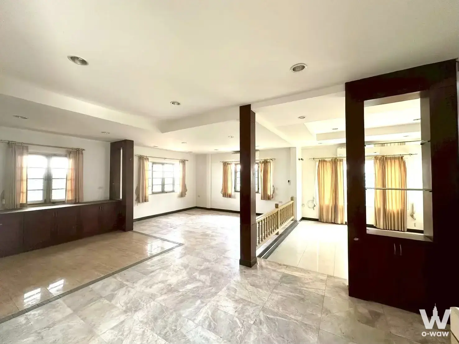 The living room of a 4-bed house for sale in Ladawan Srinakarin has high ceilings and dark wood columns