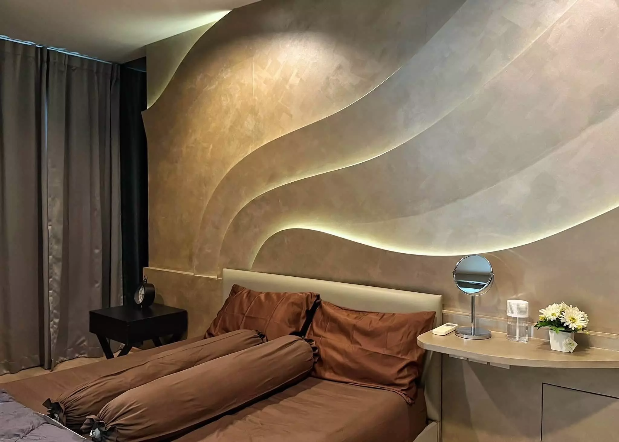 Modern bedroom in 1-bed Ideo Q Ratchathewi rental with rust linens and wave accent wall