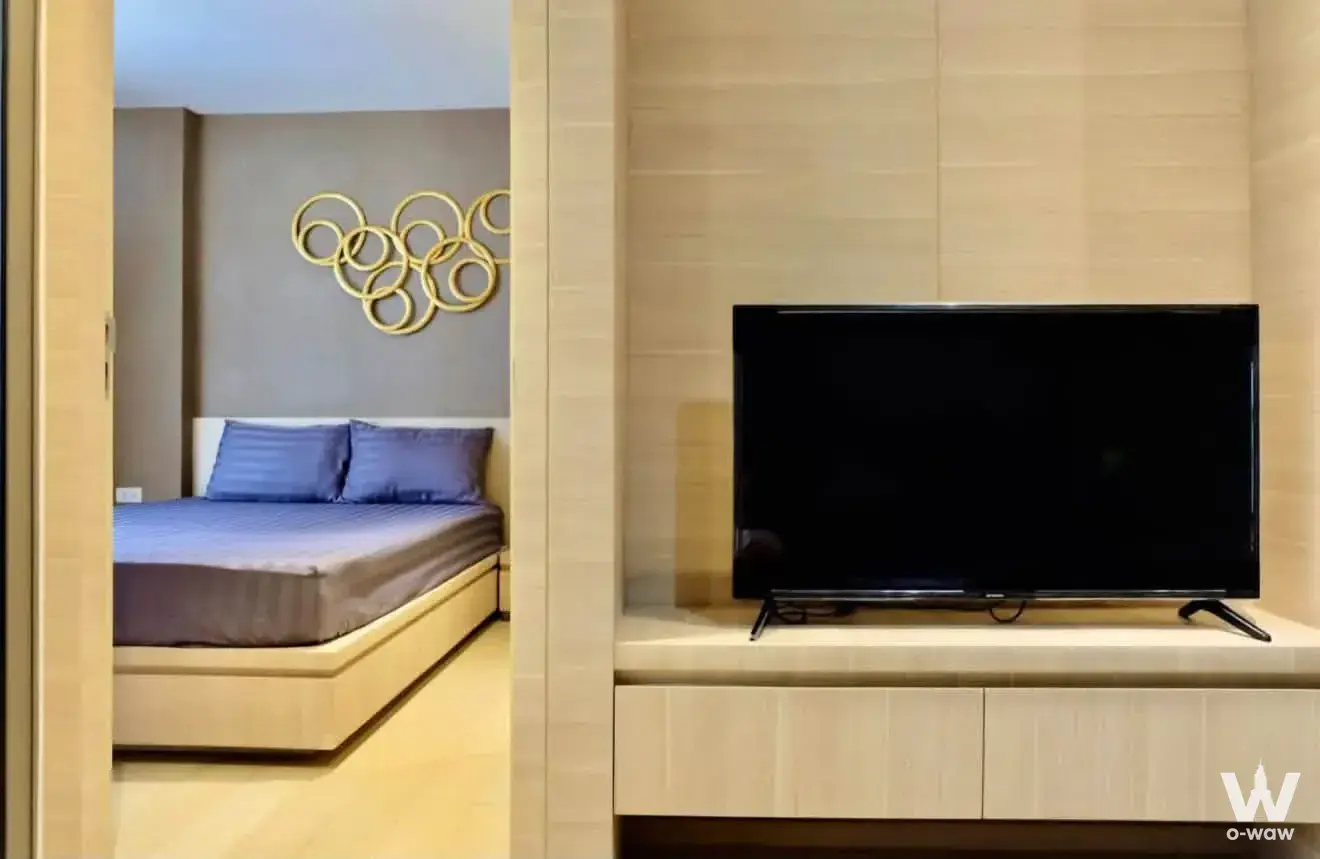 Modern bedroom with purple-blue bedding and gold wall art for a 1-bed condo in Klass Silom Condo