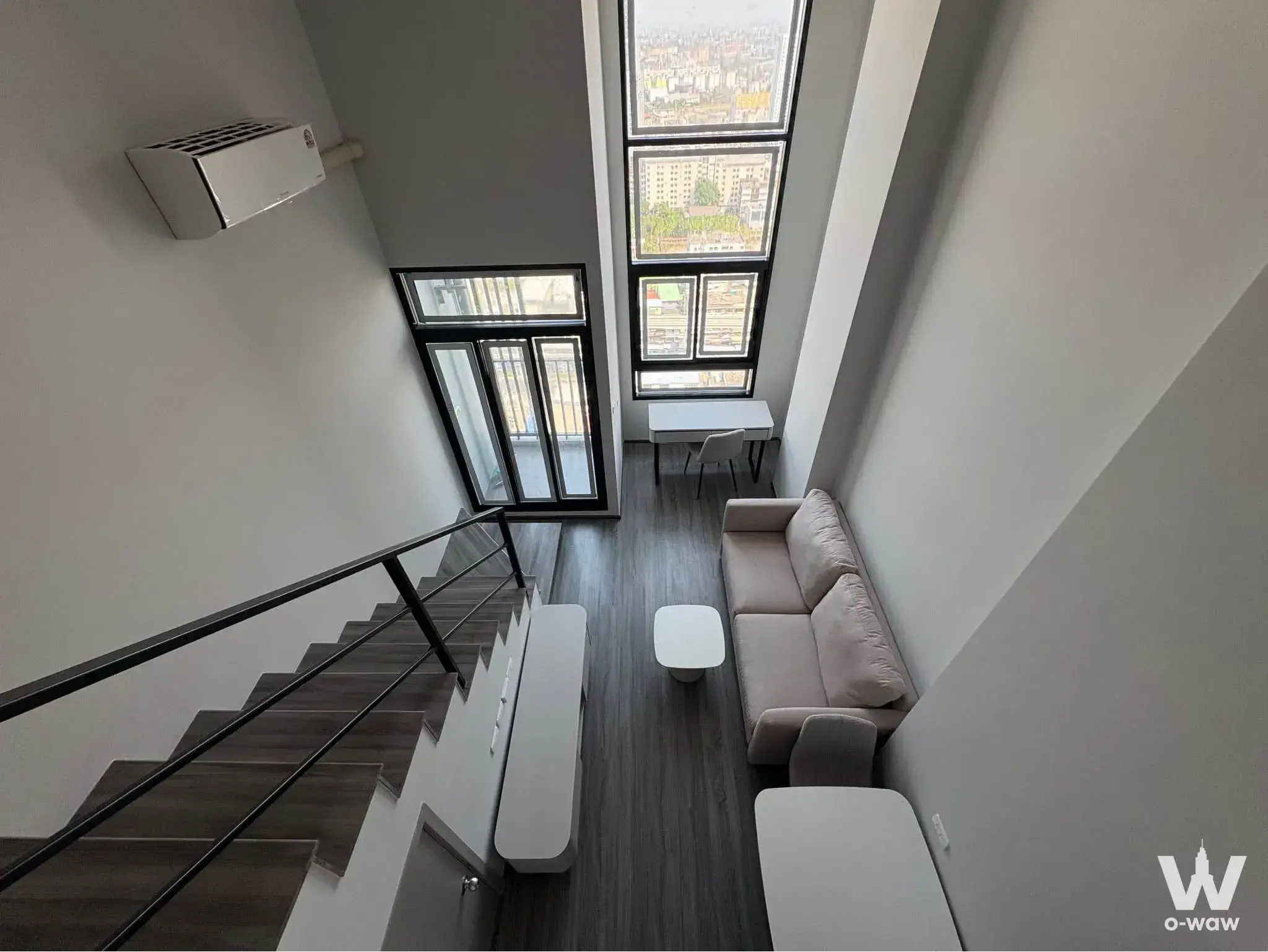 Duplex loft with wooden staircase, glass balustrade, sofa, and city view windows