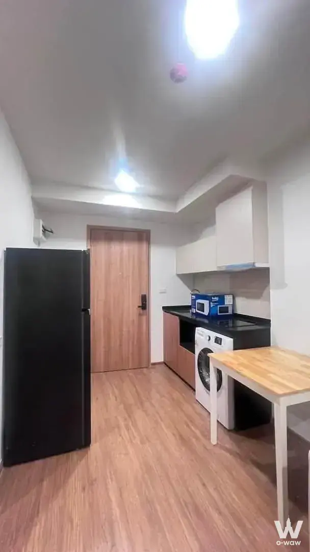 Compact 1-bed condo for sale in The LIVIN Phetkasem kitchenette with light wood laminate flooring and white cabinetry