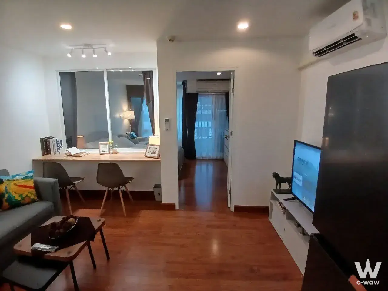 Modern living room in 1-bed Surawong City Resort condo with wood floors, grey sofa, and built-in study nook