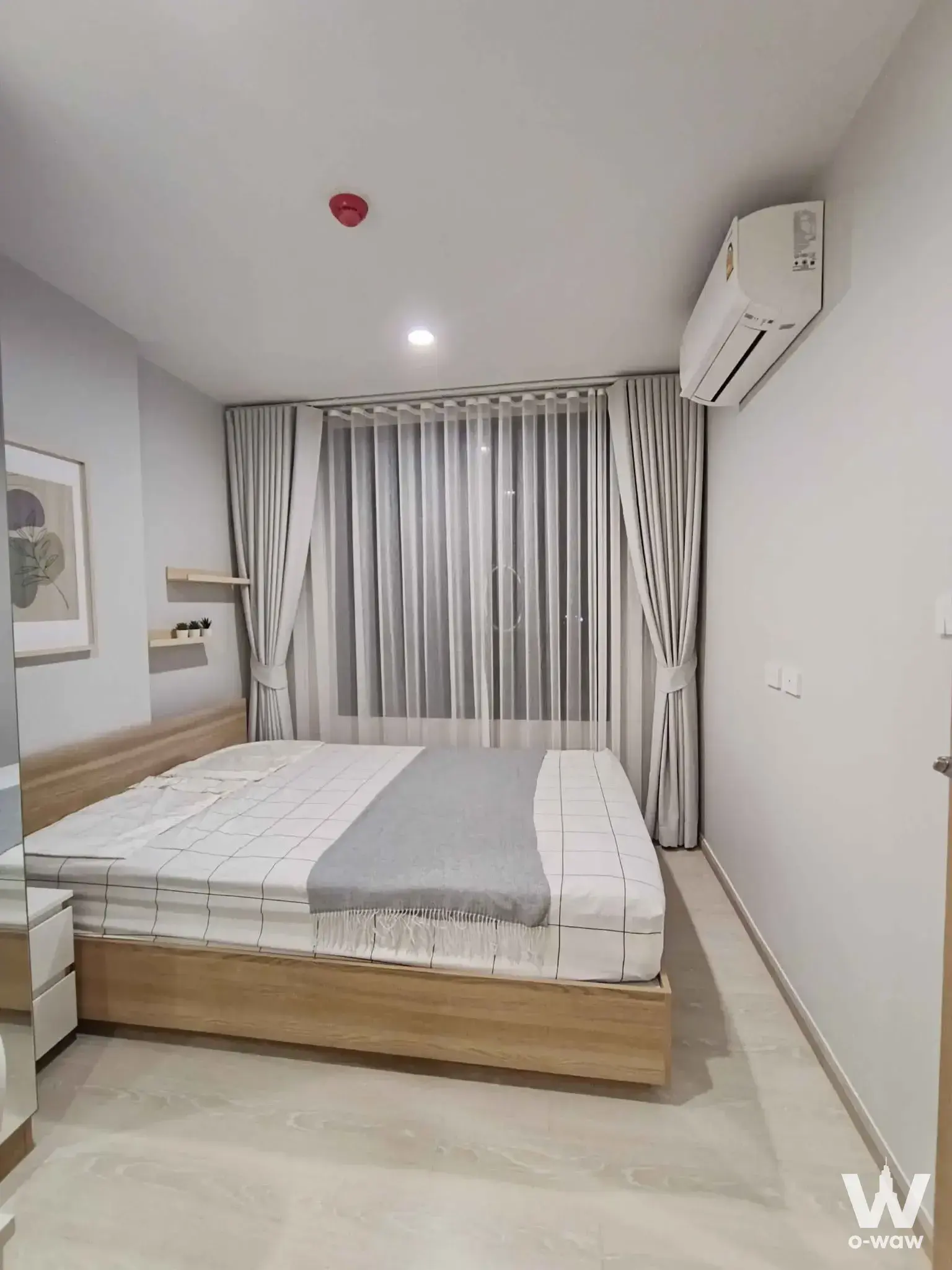 Minimalist bedroom in a Nue Connex Don Mueang rental featuring grid bedding and floating shelves