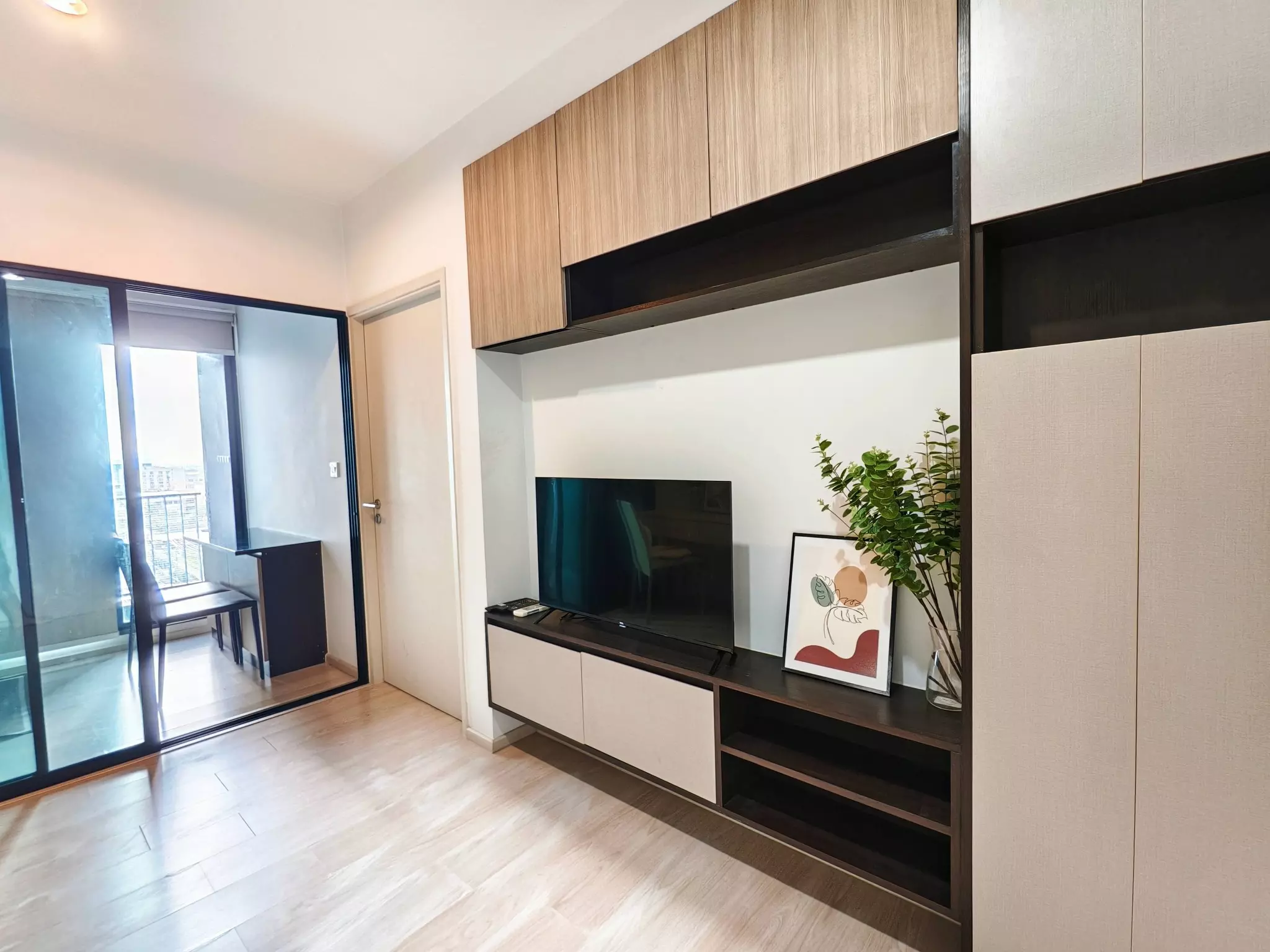 Modern living room in 1-bed condo for rent at The Gallery Bearing with dark wood entertainment unit and city view balcony