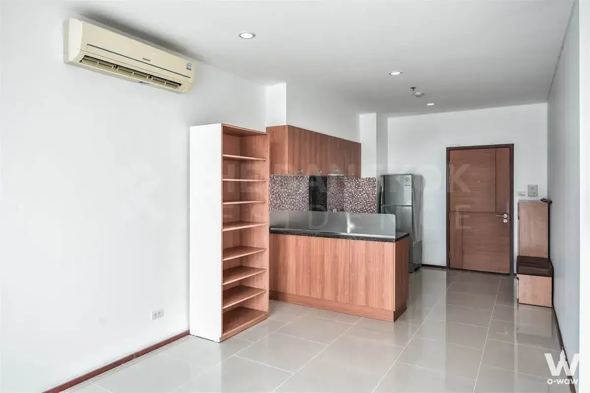 Modern unfurnished studio in Villa Sathorn condo for sale with glossy grey floors and wood kitchen cabinetry