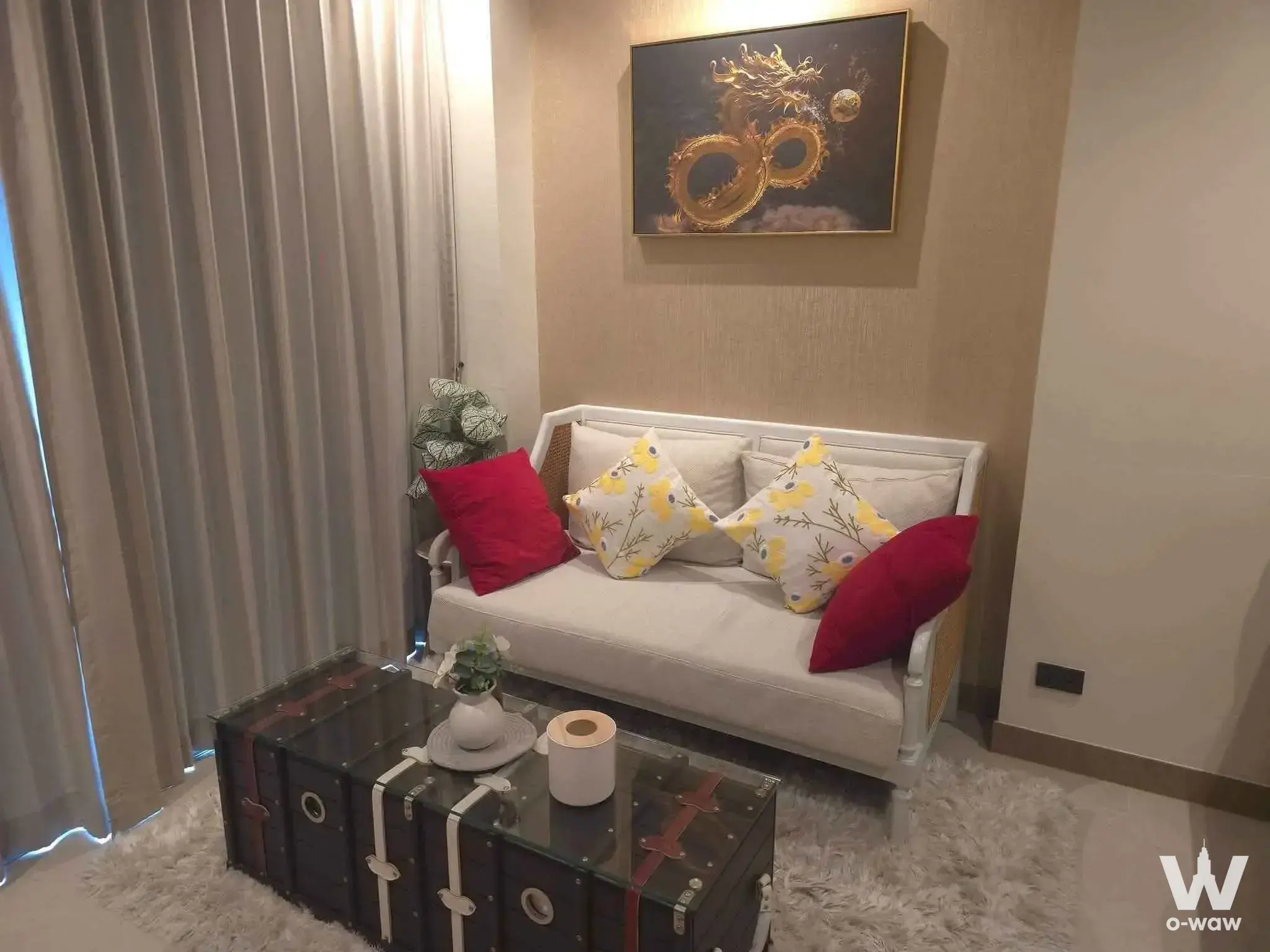 Cream cane-back sofa and gold dragon art in a cozy 1-bed condo at The Riviera Ocean Drive