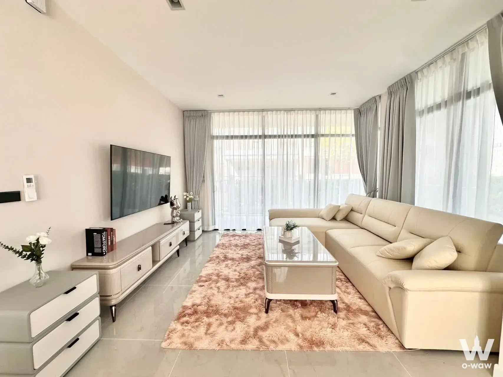 Spacious living room in a Bangkok Boulevard condo with cream sectional sofa, marble floor, and floor-to-ceiling windows