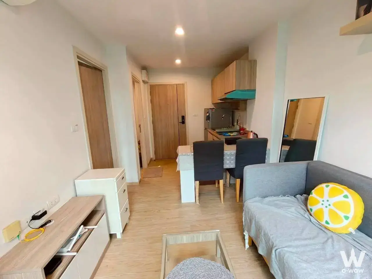 1-bed for rent at Excel Hideaway Sukhumvit 50 with grey sofa, lemon pillow, and teal kitchen hood