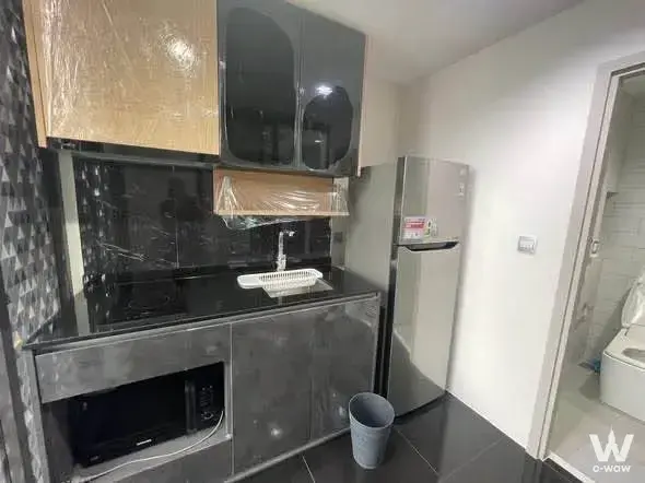 Modern kitchenette with glossy black cabinets and grey tiles in 1-bed condo for rent at THE LINE Chatuchak-Mo Chit