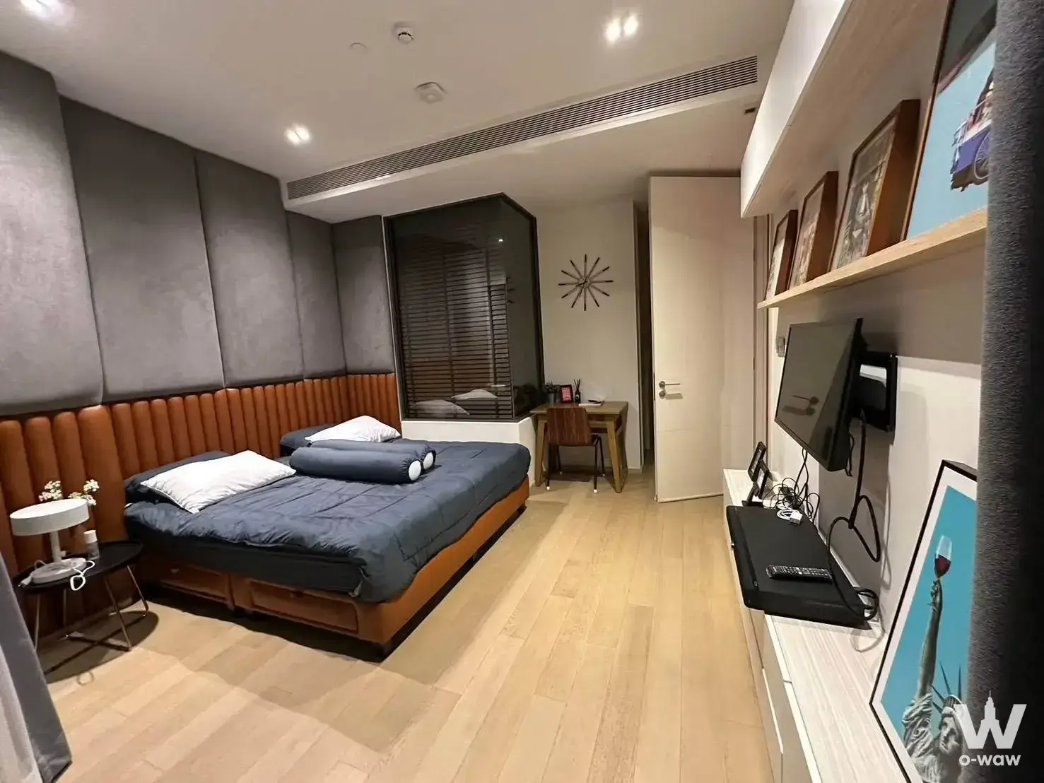 Bedroom in a 1-bed The Strand Thonglor condo for sale with a cognac leather bed and padded headboard wall