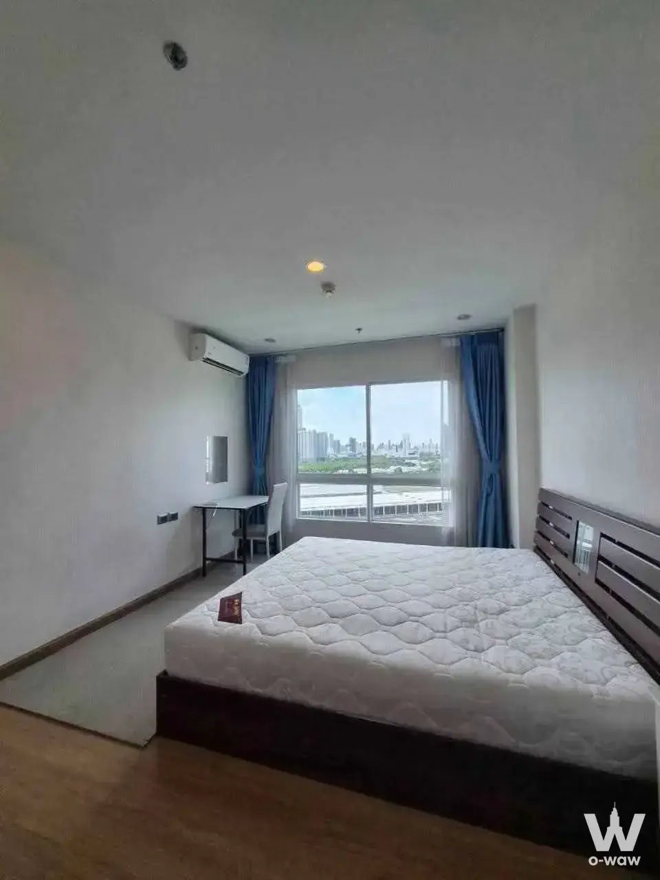 Minimalist 1-bed condo bedroom in Supalai Wellington II with desk area and blue-draped city view window