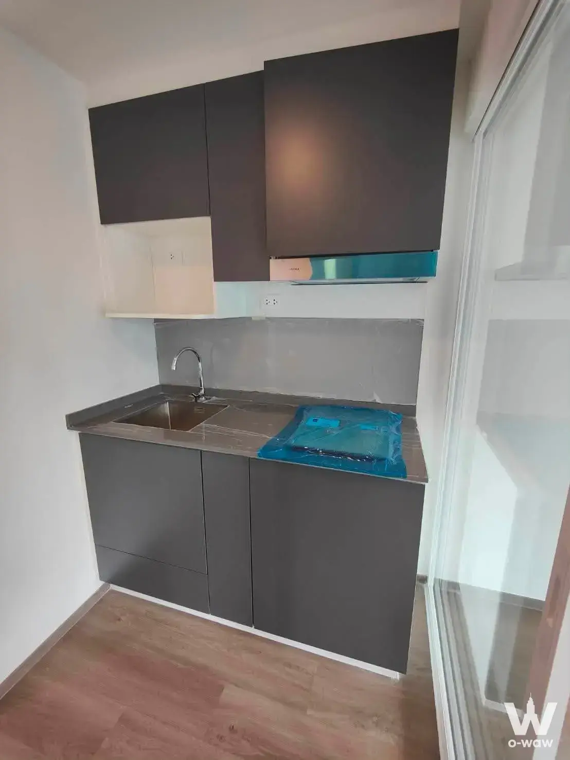 Modern kitchenette in 1-bed Supalai Veranda Rama 9 condo for sale featuring dark grey cabinets, stainless steel sink, and