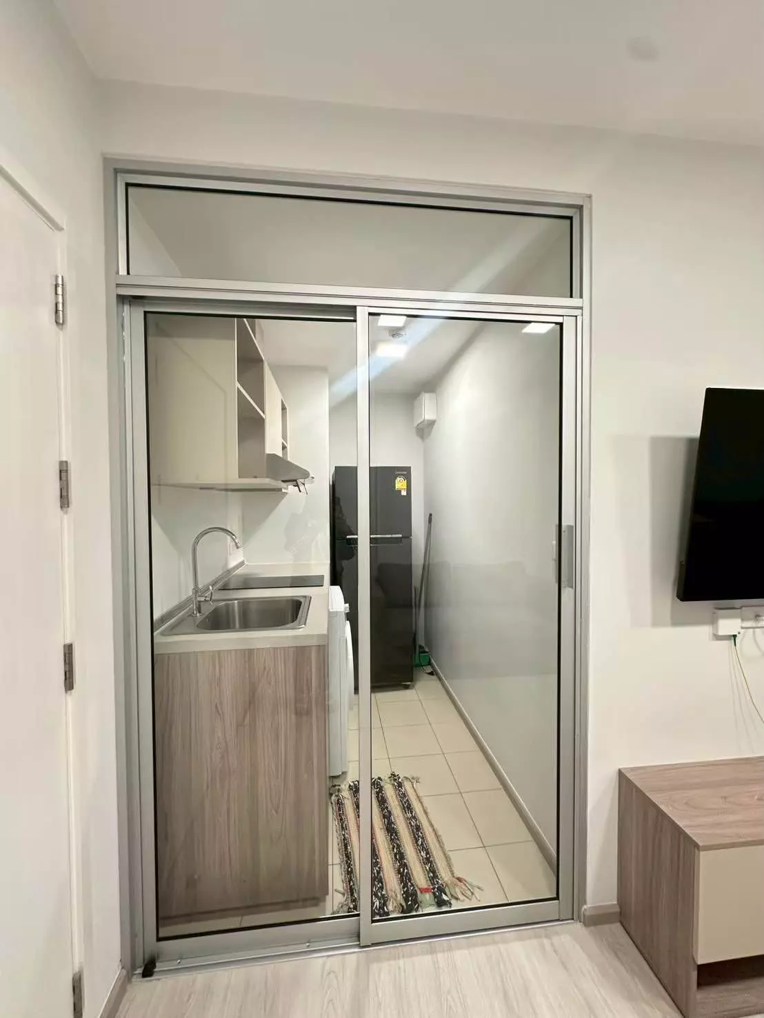 Modern 1-bed condo for rent in Plum Condo Sukhumvit 62 with open-plan living area and glass-enclosed kitchen