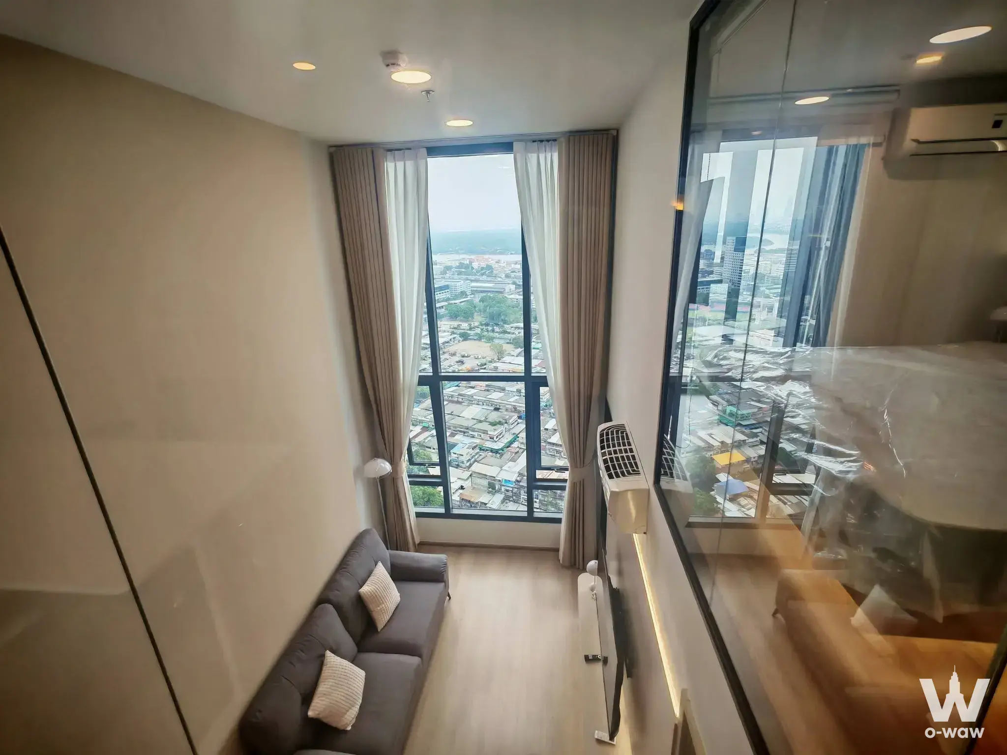Modern living room with grey sofa and city views in 2-bed condo for rent at Life Rama 4 Asoke