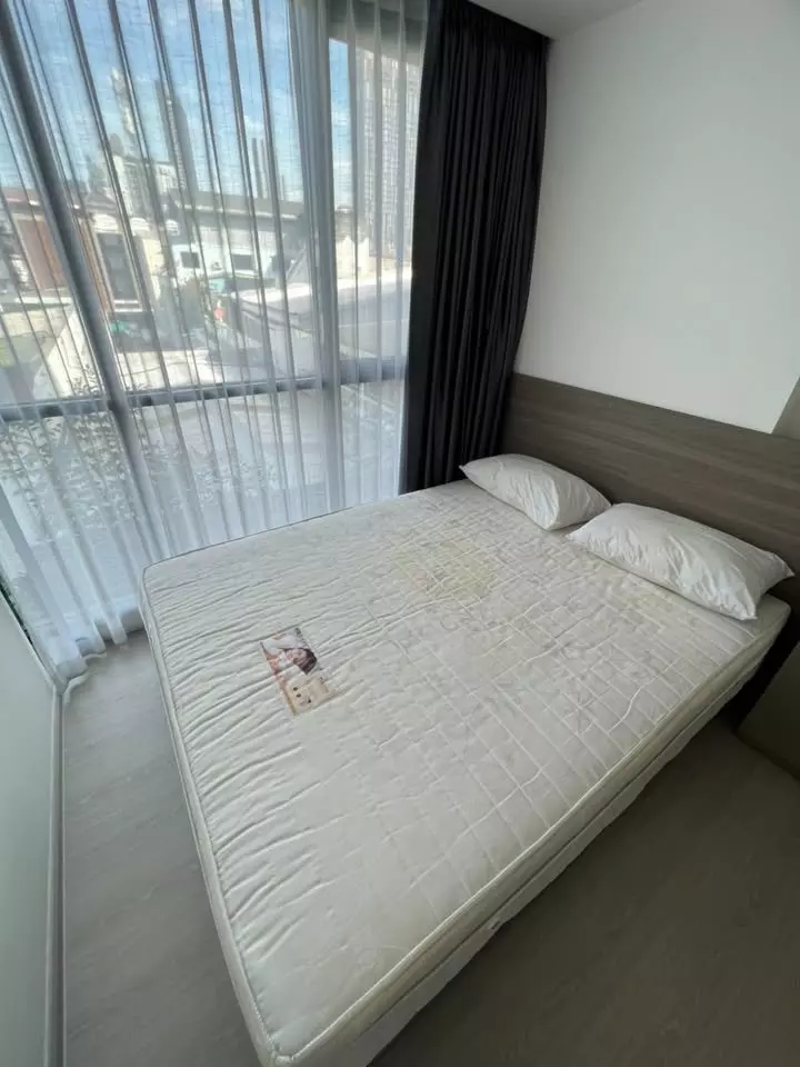 Queen bed with wood headboard in 1-bed condo for rent at VTARA Sukhumvit 36, featuring floor-to-ceiling windows and city