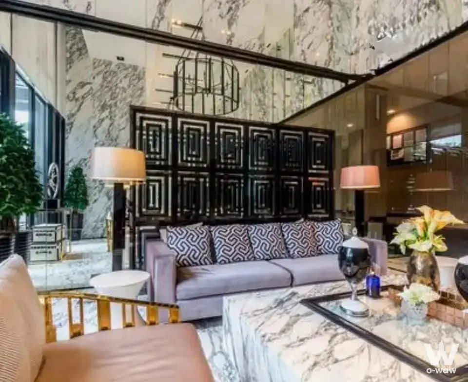 Double-height lobby lounge with marble walls and gold accents in this 2-bed THE BASE Park West condo