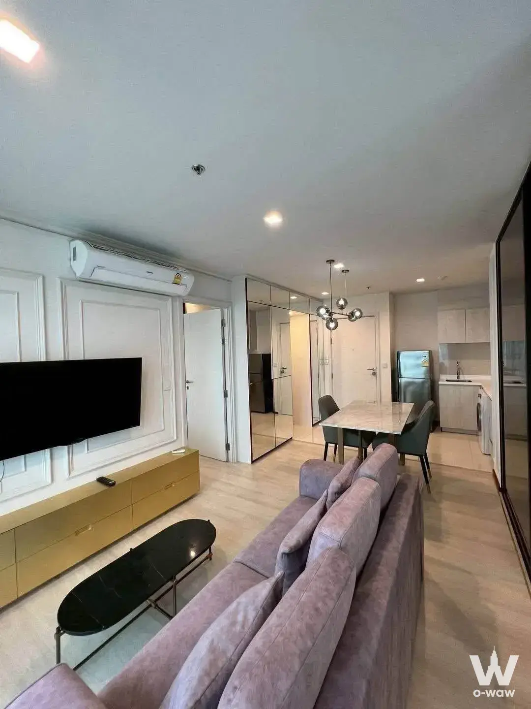 Modern living room in 2-bed condo for rent at Life One Wireless featuring mauve sofa, gold console, and mirrored walls