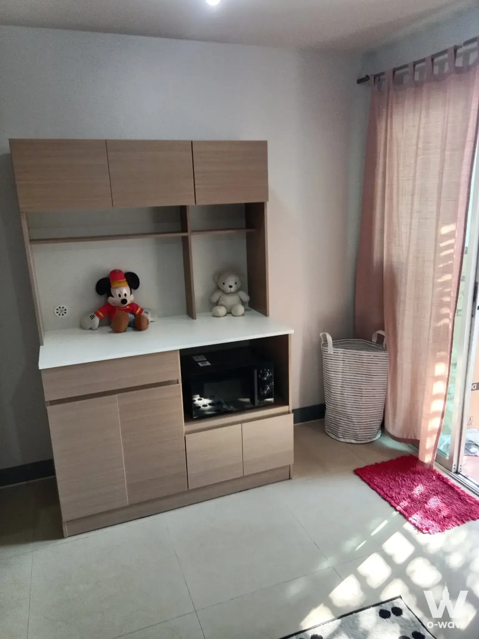 Corner storage nook with wood cabinets and pink rug in Regent Home 4 condo