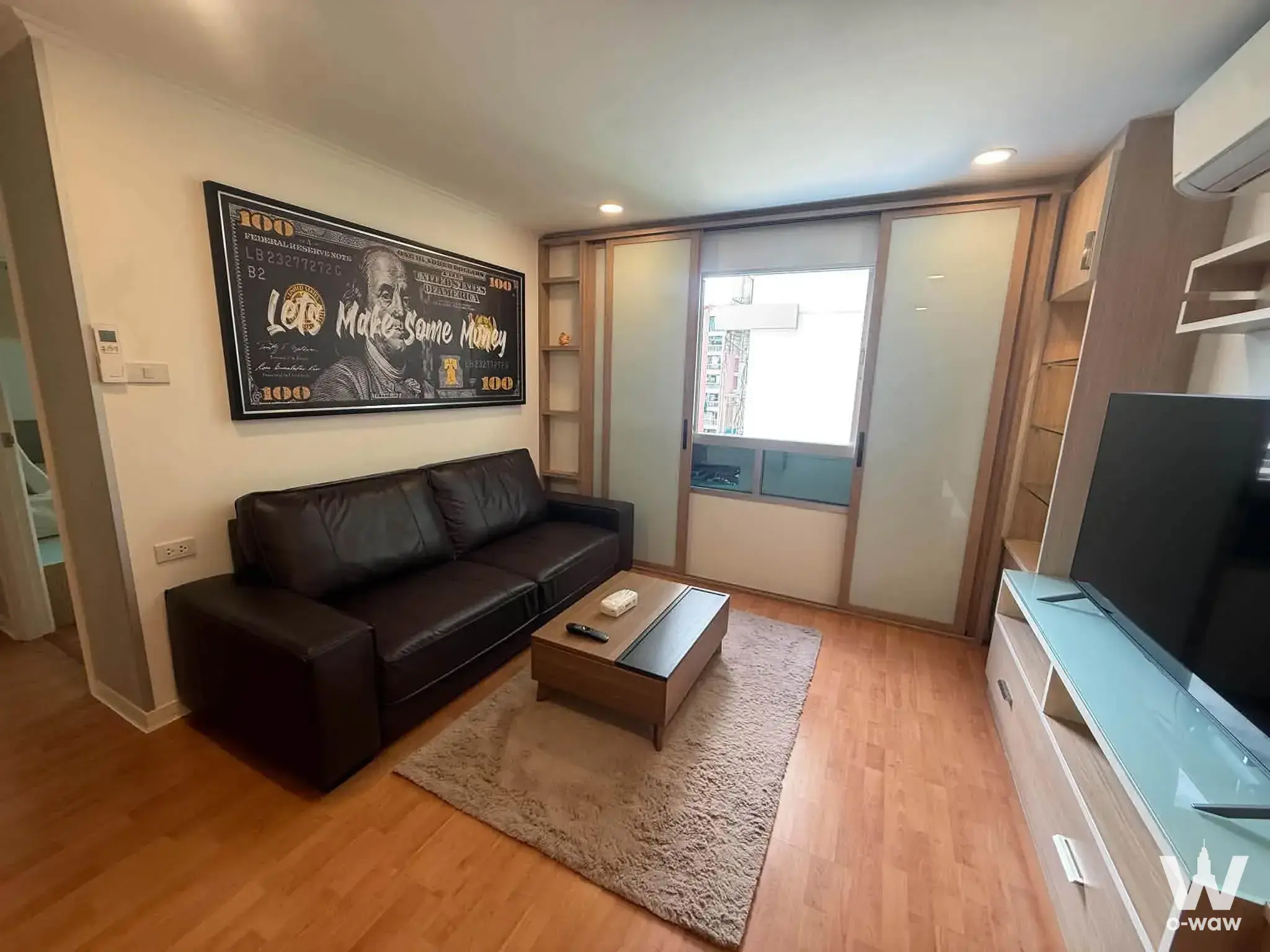 2-bed condo for rent in Lumpini Ville Cultural Center living room with dark leather sofa and stylized artwork