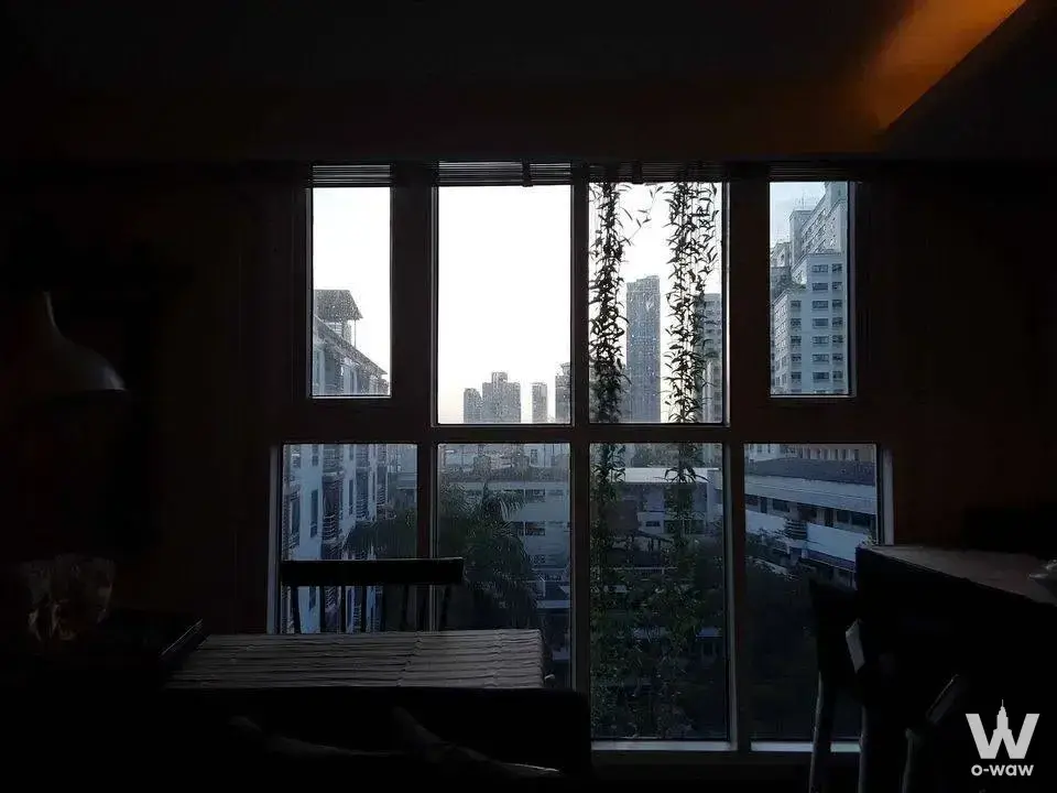 Dining area in Haven luxe house with dark wood table, hanging vines, and city skyline view through large window