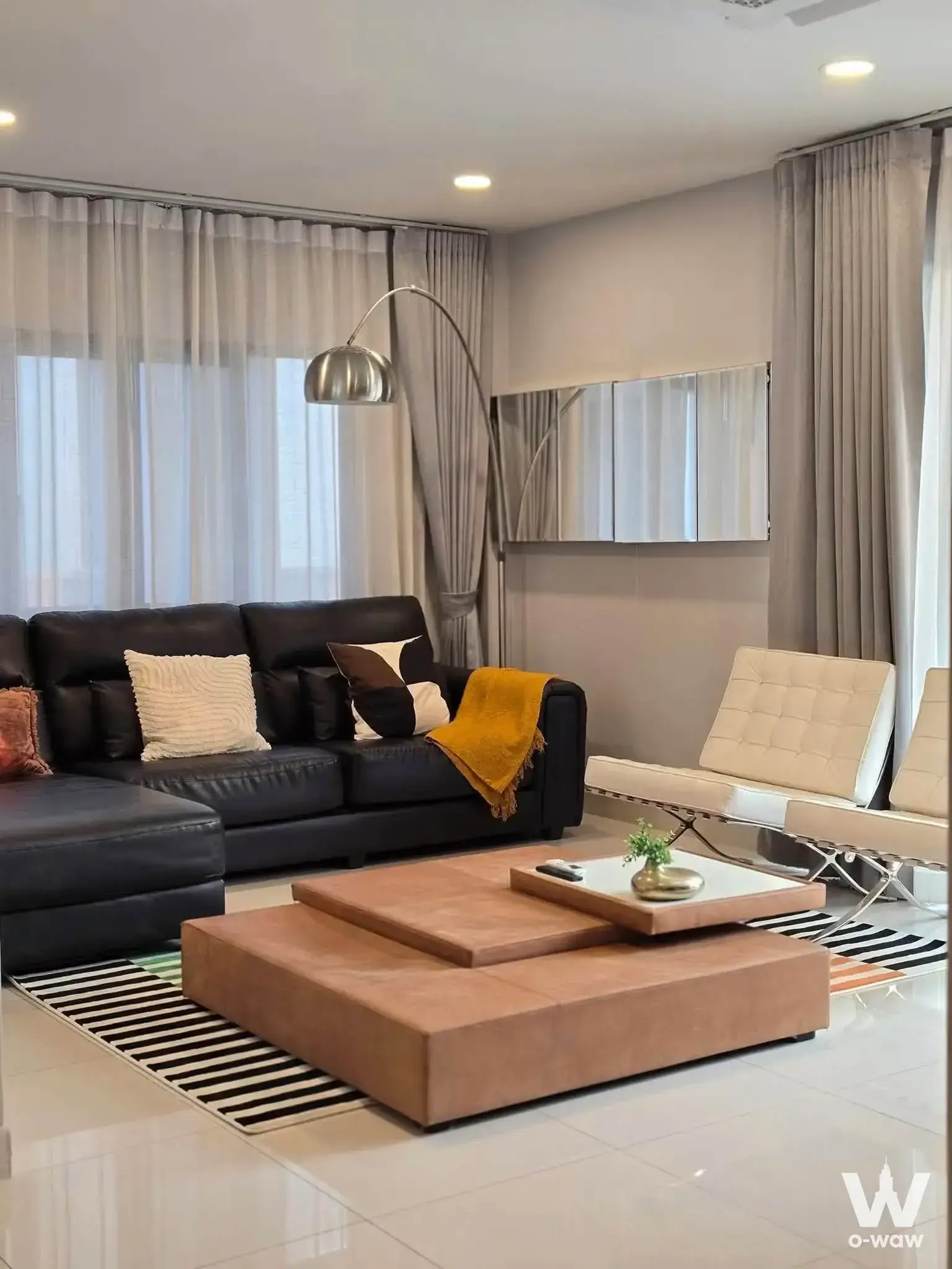 4-bed house for rent in Centro Bangna showcasing a modern living room with black leather sectional sofa