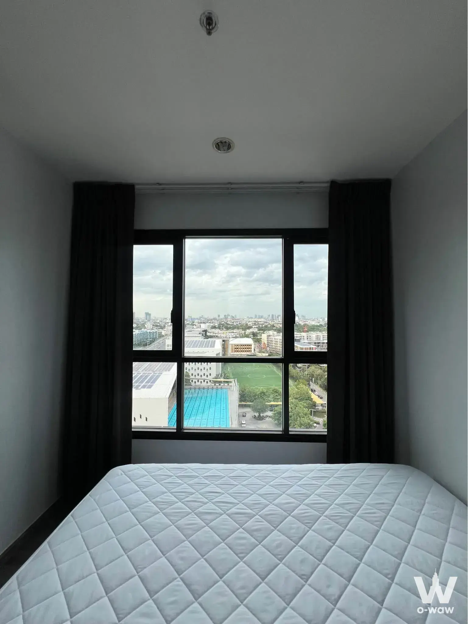 Queen bed facing a large window with city view in this The Park 1-bed condo bedroom