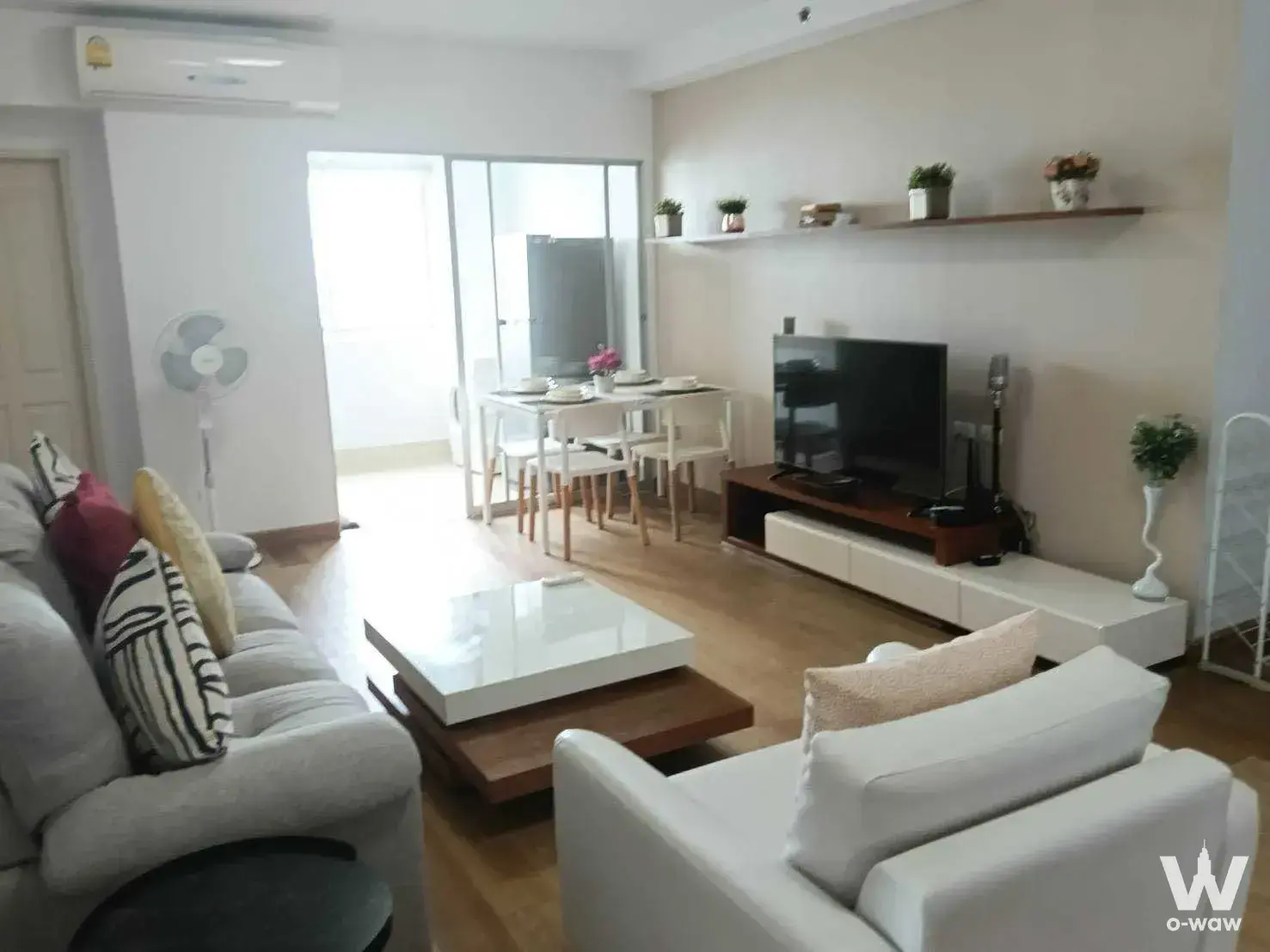 Furnished living room in Supalai Park Ekkamai with a grey sofa and white dining set