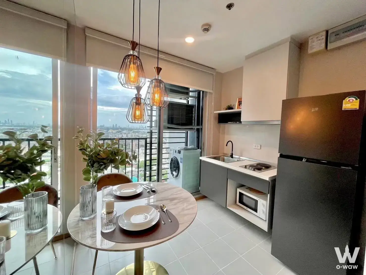 Dining area in THE BASE Sukhumvit 77 condo with marble table, pendant lights, and city skyline