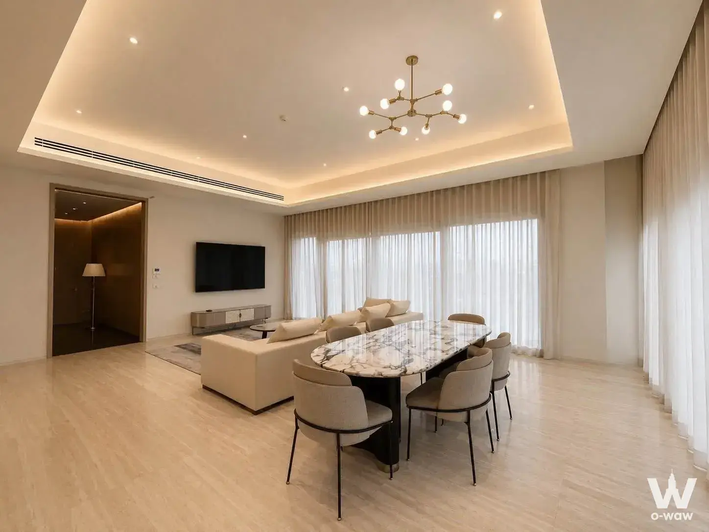 Open-plan living space in SCOPE Langsuan with a cream sectional sofa and marble dining set