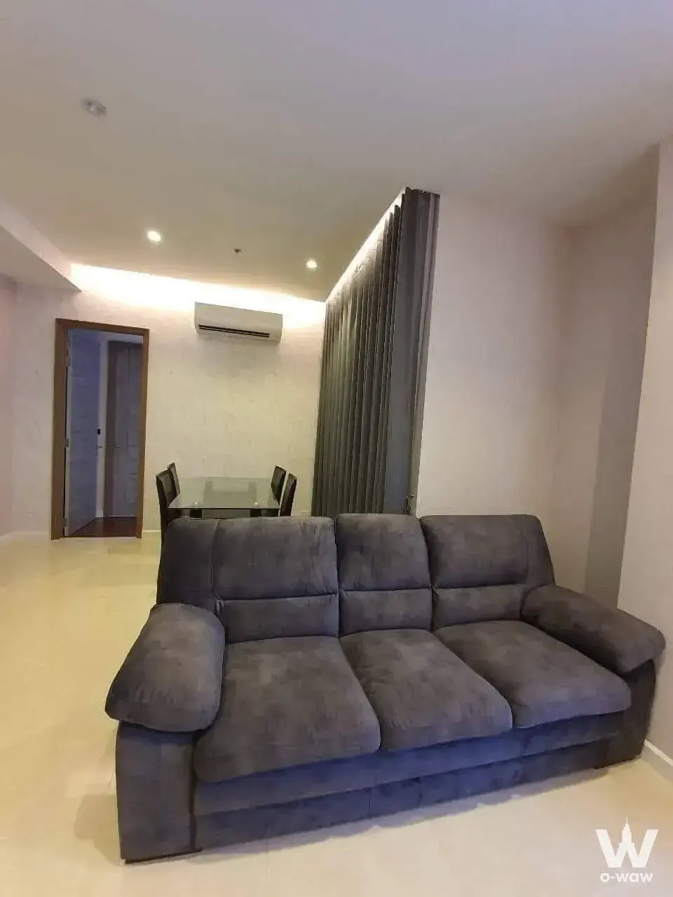 Open-plan living and dining area in a 2-bed Mayfair Place condo with grey sofa and glass table
