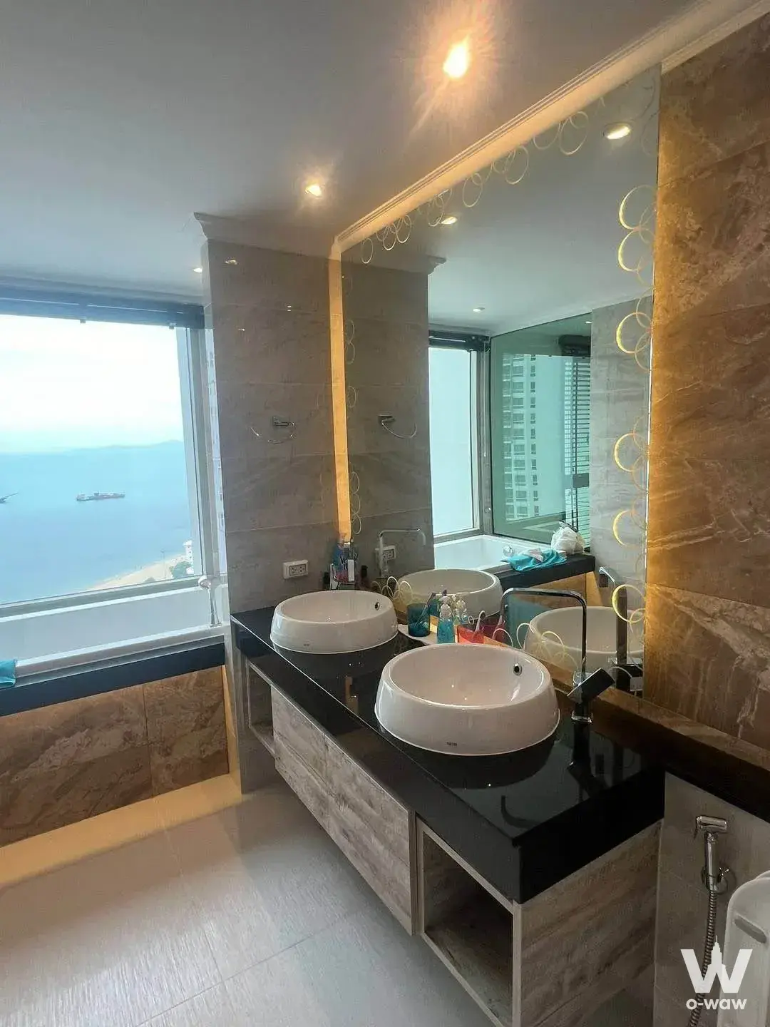 Modern bathroom with double vanity, backlit mirror, and ocean view in The Riviera Monaco