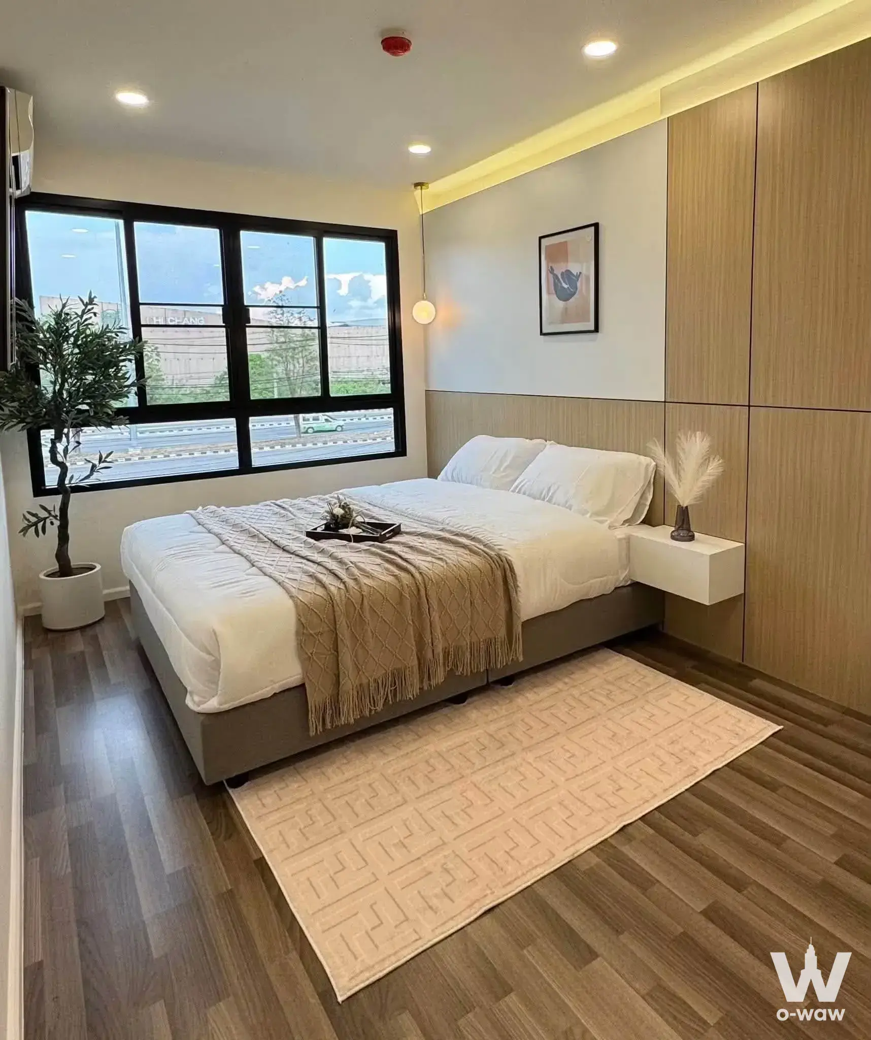 Master bedroom in Parano Condo Chiang Mai for sale with queen bed, geometric rug, and city view