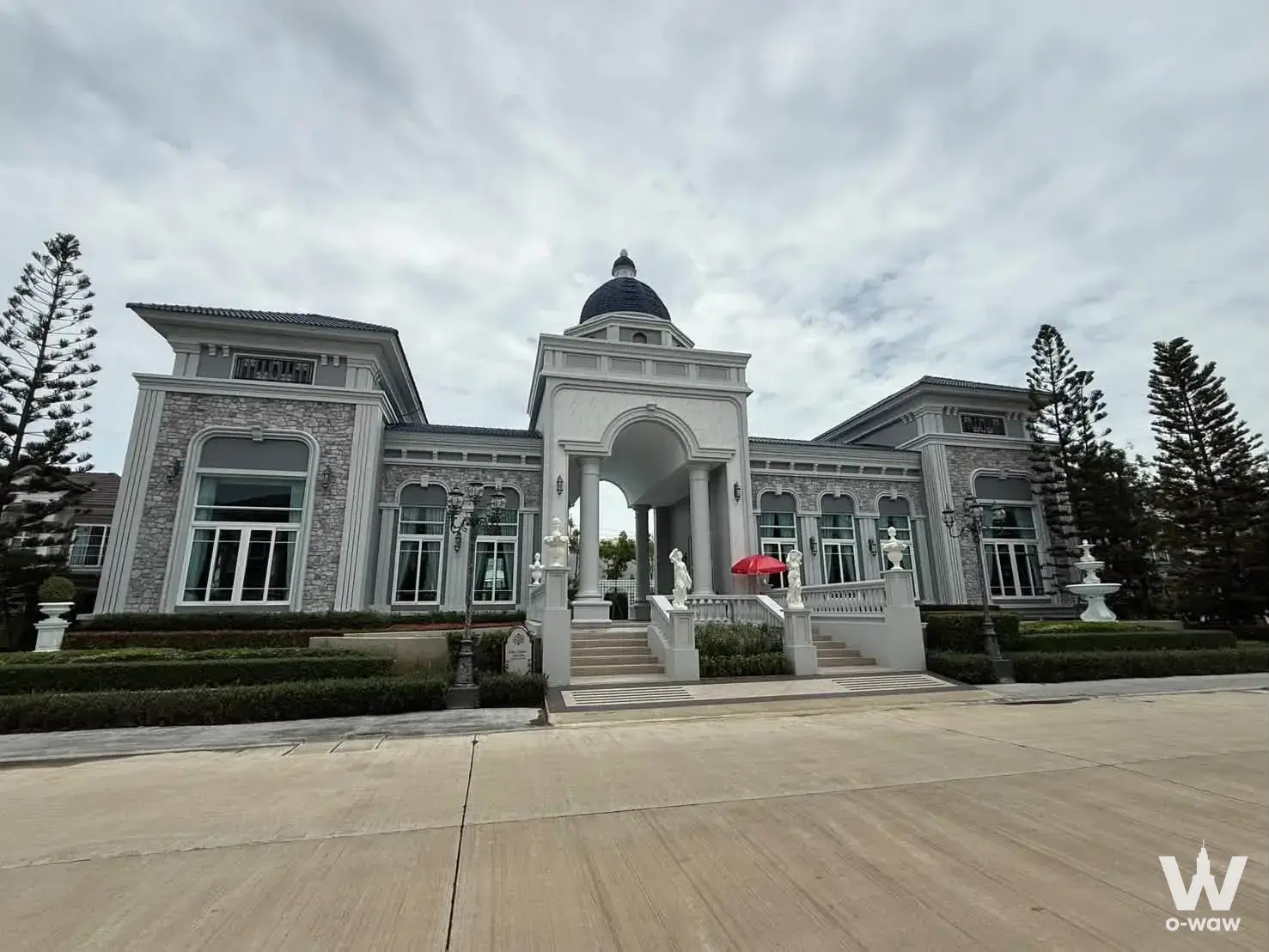 Neoclassical 4-bed house exterior for rent in Grandio Bangna KM.5 with white columns, arched portico, and fountain