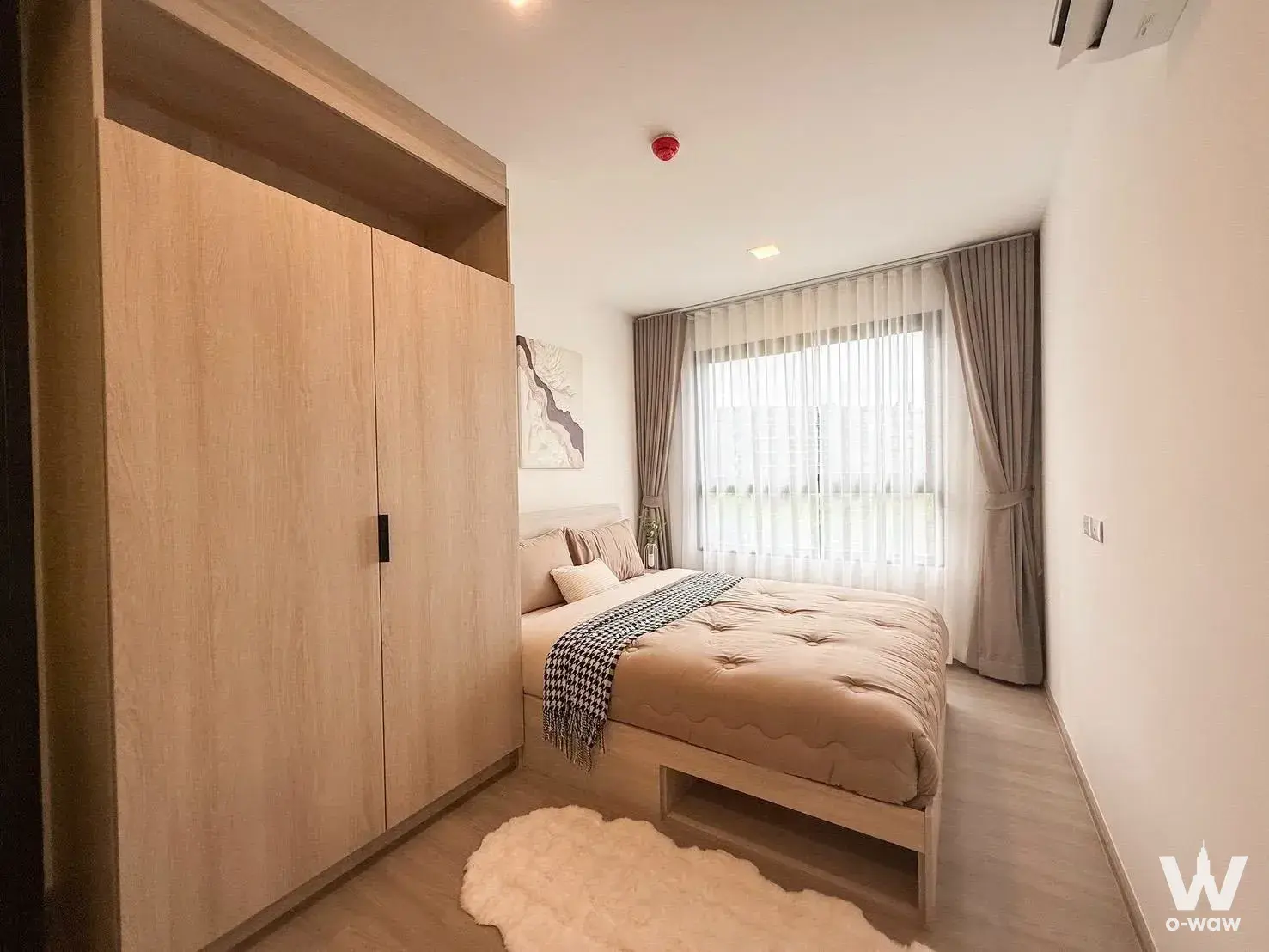 Fully furnished 1-bed condo bedroom in The Base Bukit Phuket with floor-to-ceiling wardrobes and warm wood tones