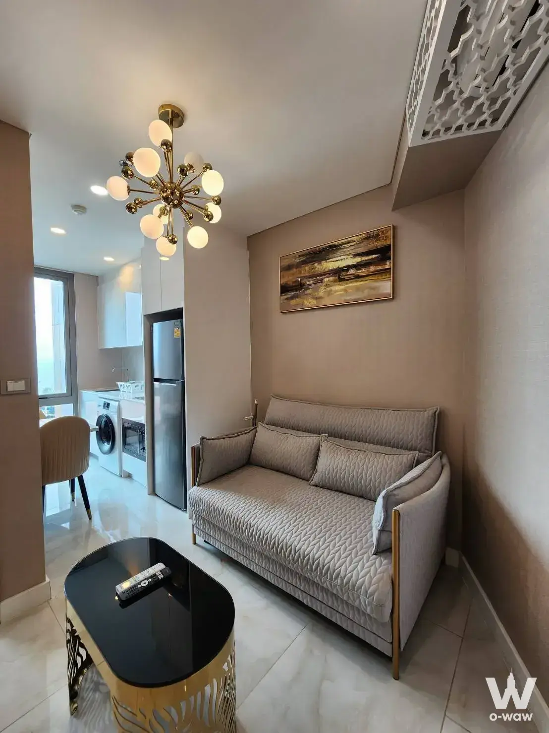 Living room in a 1-bed condo for sale at Copacabana Beach Jomtien with a taupe sofa and gold sputnik chandelier