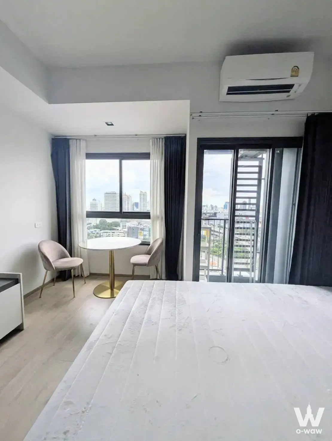 IDEO Rama 9 master bedroom with blush-pink chairs, gold accents, and balcony access