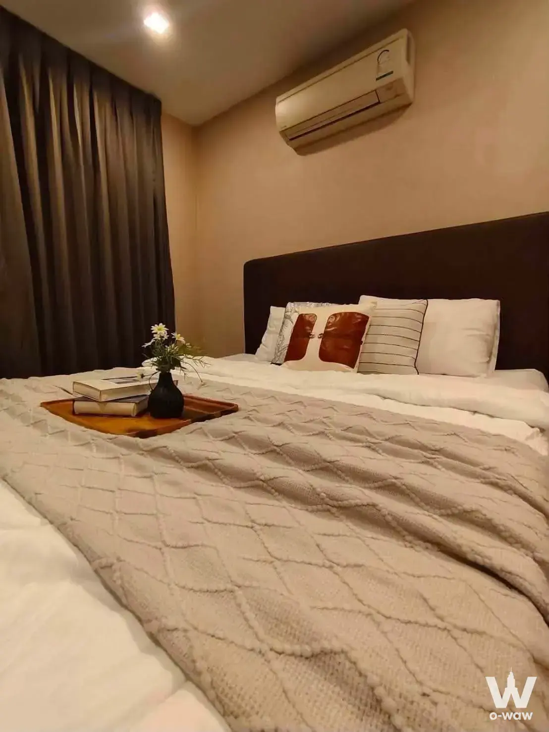 Cozy bedroom with dark brown upholstered headboard, beige knit throw, and decorative pillow accents