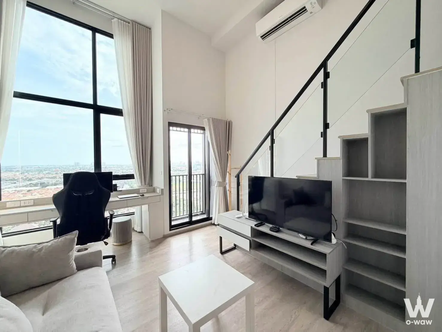 Modern 1-bed condo living room in Origin Plug & Play Nonthaburi with high ceilings and city skyline view