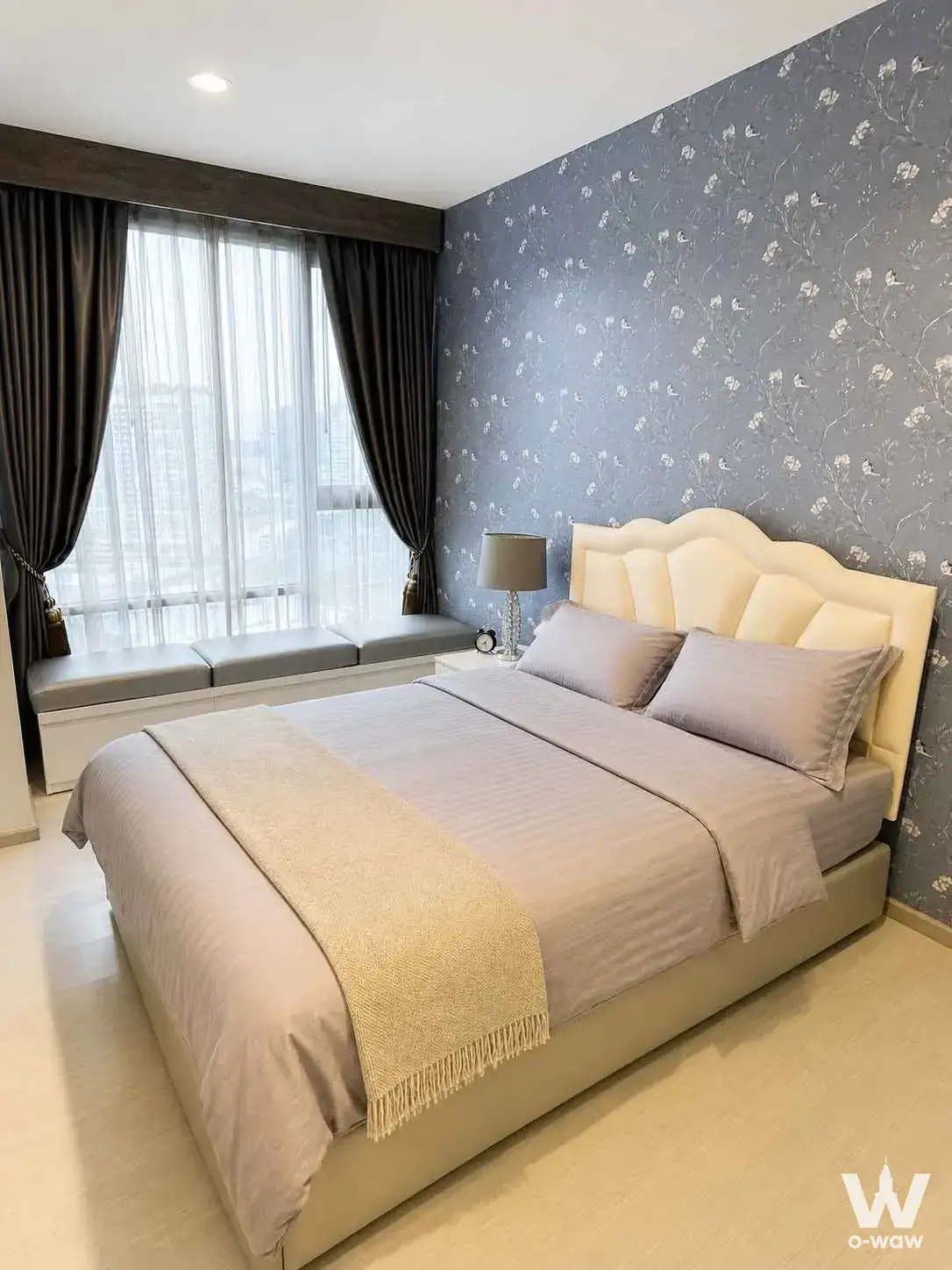 Master bedroom in Rhythm Sukhumvit 42 condo with cream scalloped headboard and built-in window seat overlooking the city