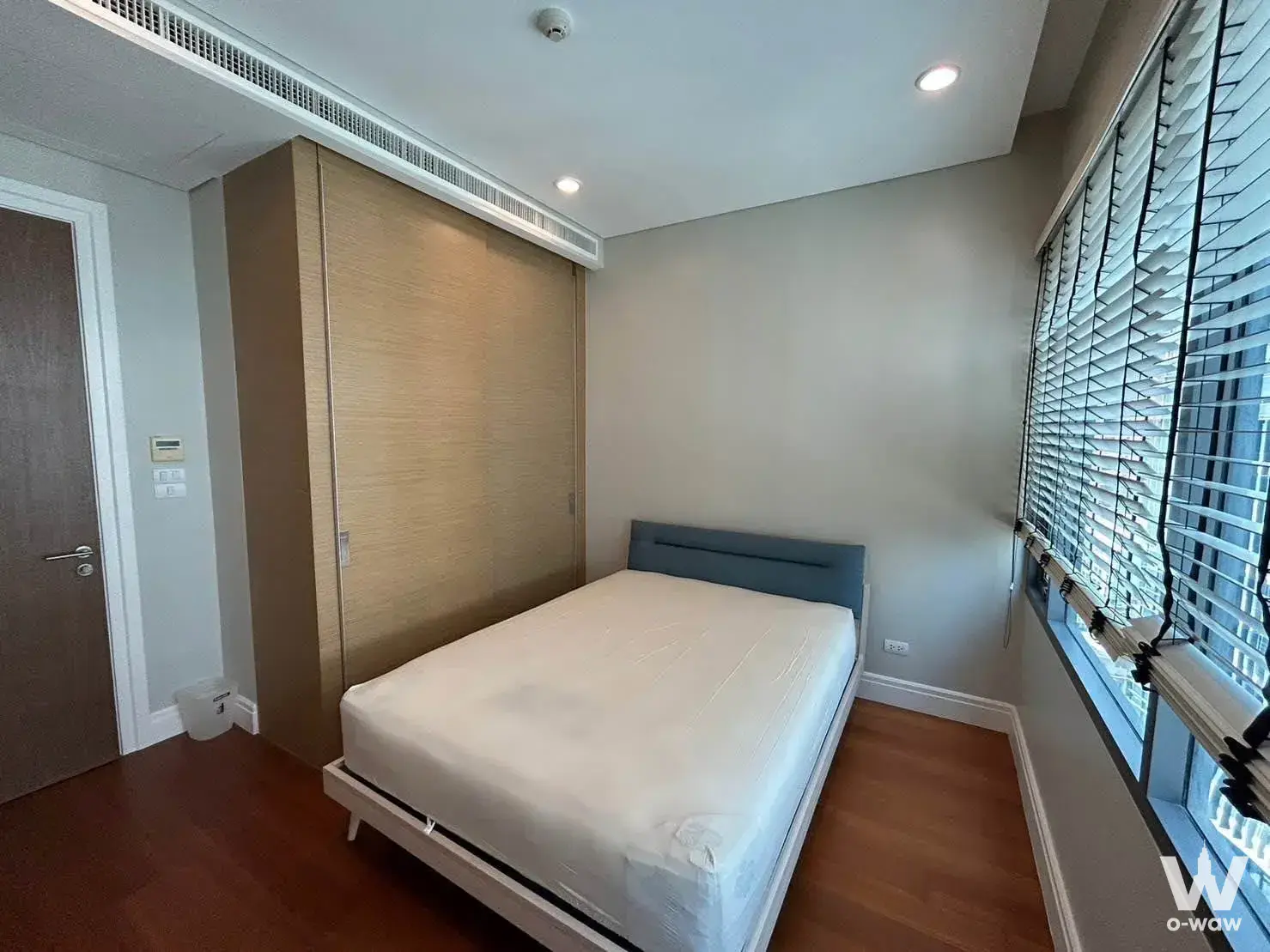 Bedroom in a Bright Sukhumvit 24 condo with a blue headboard bed and large built-in wardrobe
